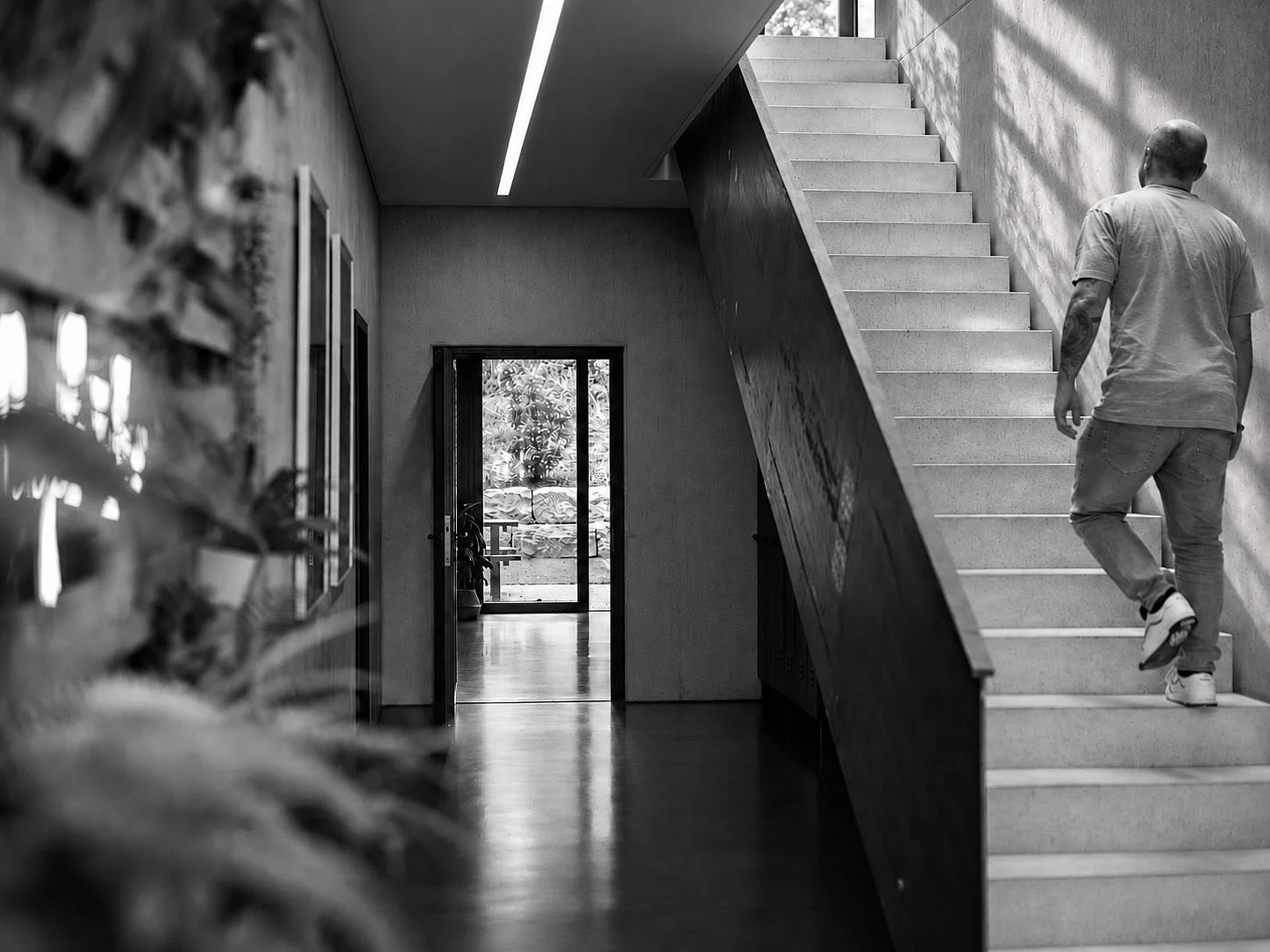 Ein Mann in lässiger Kleidung steigt eine moderne Treppe in einem hellen Innenraum hinauf